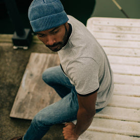 fit model sitting on boat dock wearing The Heavy Bag Ringer Tee in Aluminum