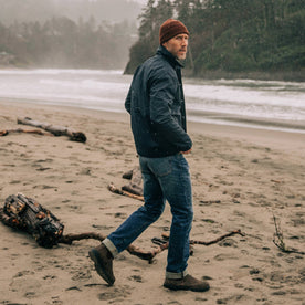 fit model walking on a sandy beach in The Watts Jacket in Dark Navy