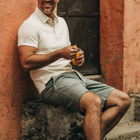 fit model wearing The Apres Short in Olive Pin Dot, eating, sitting on ledge