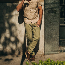 fit model wearing The Camp Pant in Olive Herringbone, against wall
