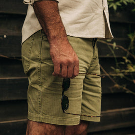 fit model wearing The Camp Short in Olive Herringbone, holding sunglasses