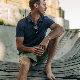 fit model wearing The Heavy Bag Polo in Navy Stripe, sitting on wood