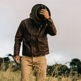 fit model wearing The Hangar Jacket in Espresso, holding hat