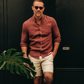 fit model wearing The Jack in Rust Linen, looking at camera, next to plant