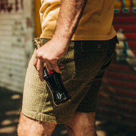 fit model wearing The Trail Short in Rain Drop Camo, holding coke