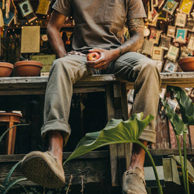 fit model wearing The Camp Pant in Stone Boss Duck, eating apple, sitting