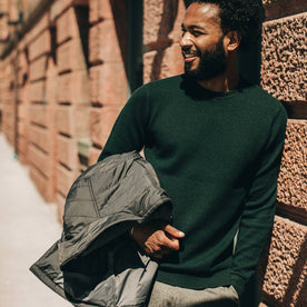 fit model wearing The Double Knit Sweater in Forest, holding jacket, looking left