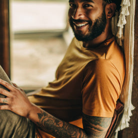 fit model wearing The Merino Tee in Heather Saffron, reclining, shoulder detail