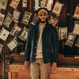 fit model wearing The Ojai Jacket in Washed Indigo Herringbone, books on wall behind, looking at camera