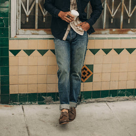 fit model wearing The Slim Jean in 18 Month Wash Organic Selvage, cuffed, holding coffee