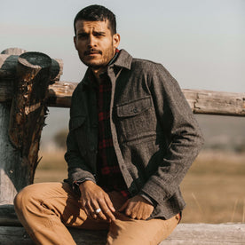 fit model wearing The Explorer Shirt in Coal Herringbone Wool sitting on a fence