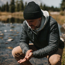 Fit model crouching wearing The Waffle Beanie in Coal Merino