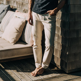 fit model wearing The Slim Jean in Natural Organic Selvage on a porch