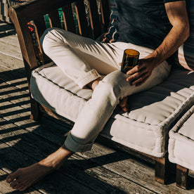 fit model sitting on a couch in The Slim Jean in Natural Organic Selvage