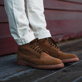 fit model wearing The Trench Boot in Butterscotch Weatherproof Suede, next to red wall