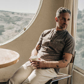 our fit model wearing The Short Sleeve Bandit in Tobacco Hemp, sitting back drinking coffee