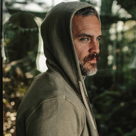 our fit model wearing The Après Hoodie in Olive—hoodie up over head