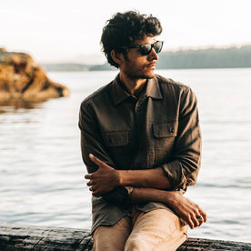 our fit model wearing The Corso in Walnut Double Cloth—sitting on log near beach