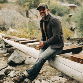 fit model wearing The Decker Jacket in Wool Beach Cloth, sitting on wood beam