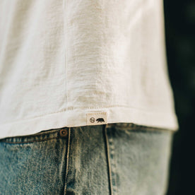 our fit model wearing The Standard Issue Tee in Natural Hemp—logo detail shot