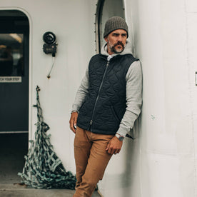 our fit model wearing The Vertical Vest in Charcoal—against a wall, looking right