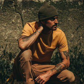 fit model wearing The Heavy Bag Tee in Saffron, kneeling, looking right
