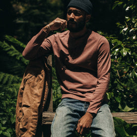 fit model wearing The Heavy Bag Henley in Burgundy, sitting on fence