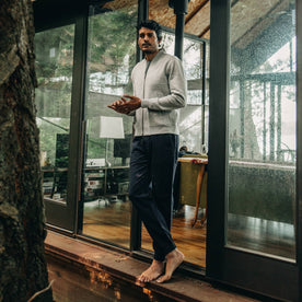 our fit model wearing The Heavy Bag Bomber in Heather Grey Fleece standing out on the porch of cabin looking at camera