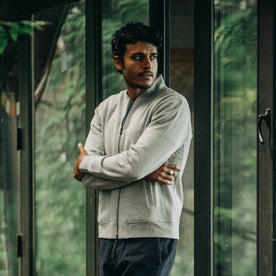 our fit model wearing The Heavy Bag Bomber in Heather Grey Fleece looking over left shoulder with arms crossed