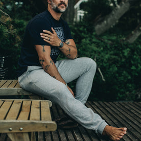 our fit model wearing The Heavy Bag Pant in Heather Grey Fleece sitting down showing entire right side