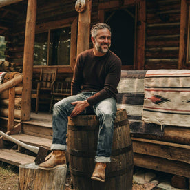 our fit model wearing The Lodge Sweater in Chocolate—sitting on barrel