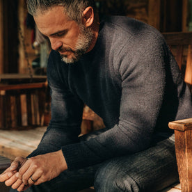 our fit model wearing The Lodge Sweater in Navy—sitting on bench
