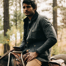 fit model wearing The Rover Jacket in Ripstop Slate Dry Wax, on horse, looking left