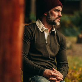 fit model wearing The Rugby Shirt in Cypress, resting against wood beam