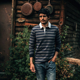 fit model wearing The Rugby Shirt in Navy Stripe, walking near cabin