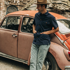 our fit model wearing The Caravan Shirt in Navy Seersucker—resting against car 
