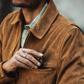 fit model wearing The Wyatt Jacket in Cognac Suede, putting sunglasses in front pocket