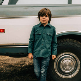 our fit model wearing The Little Yosemite Shirt in Deep Ocean—sitting against a truck
