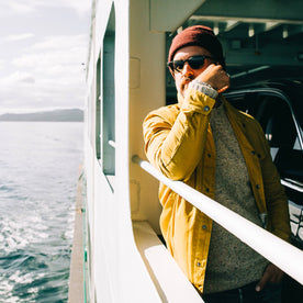 fit model wearing The Lombardi Jacket in Mustard Dry Wax, side shot on ferry