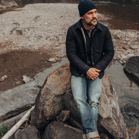 out fit model wearing The Wilton Jacket in Navy Birdseye Wool—sitting on rock