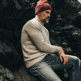 our fit model wearing The Seafarer Sweater in Natural Donegal—sitting on a rock