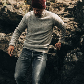 our fit model wearing The Seafarer Sweater in Natural Donegal—looking down near rocks