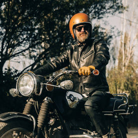 our fit model wearing The Band Collar Moto Jacket—on bike, looking left