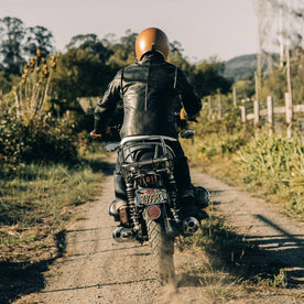 our fit model wearing The Band Collar Moto Jacket—driving away on bike